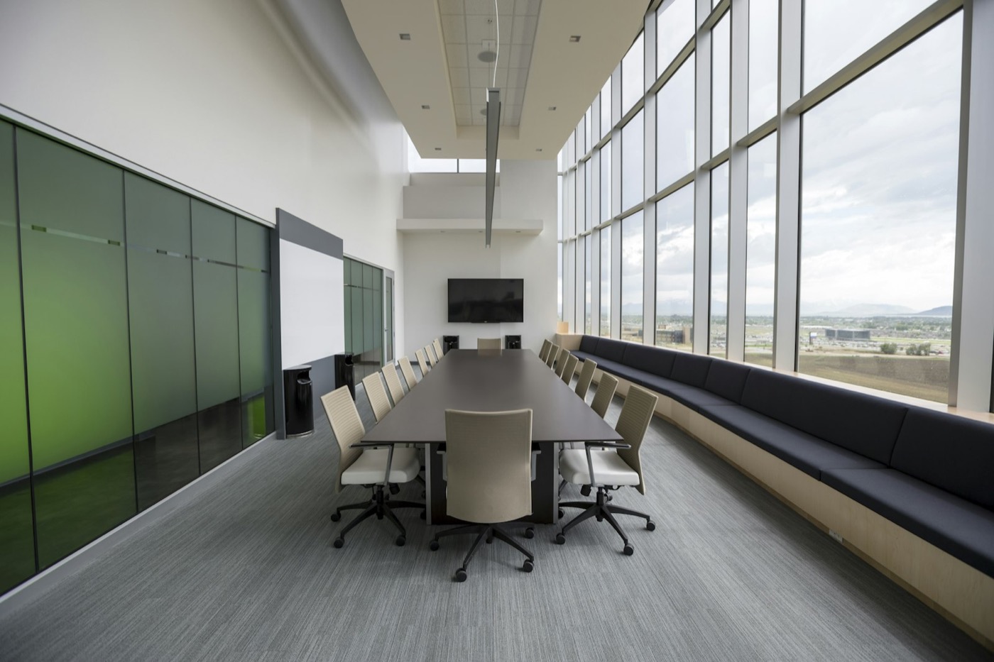 An empty modern conference room with a long table, bench seating and floor-to-ceiling windows